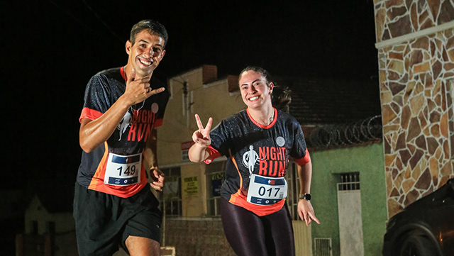 Dois atletas cruzam uma prova noturna de corrida